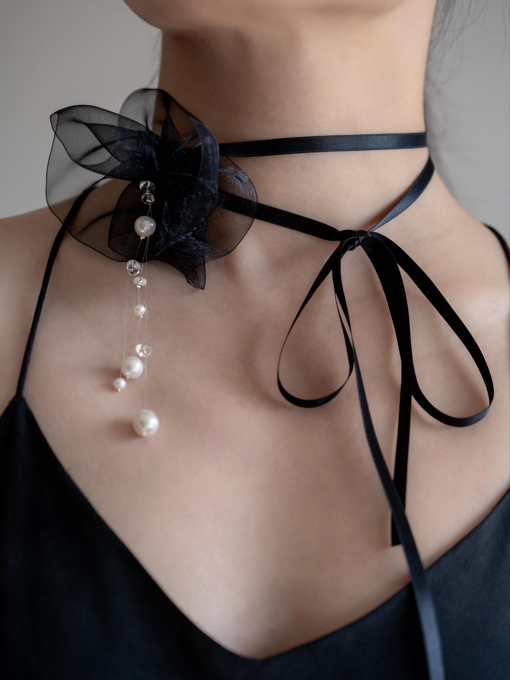 Black floral choker with pearls on a plain background